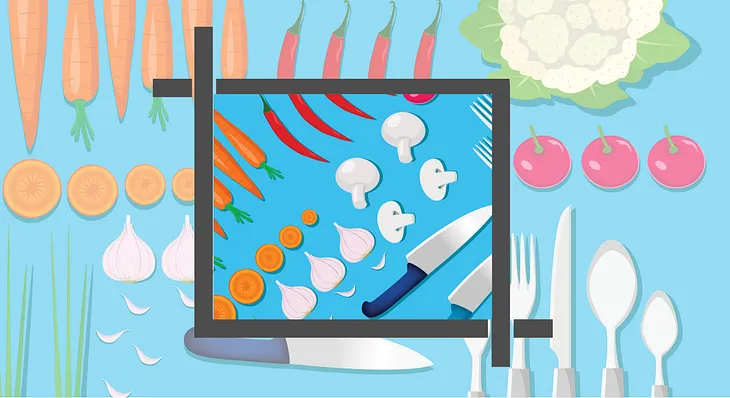 Vegetables and silverware organized on a table top and shown inside a cropped view as if in a layout by a graphic designer