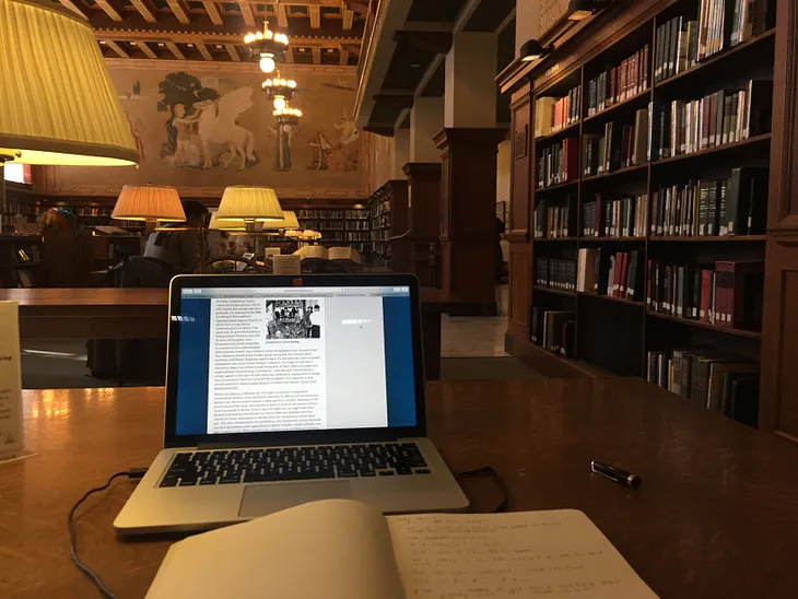 Laptop and notebook on a table in a library reading room