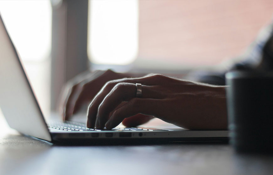 Close-up of hands typing on a laptop keyboard