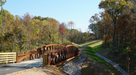 Amidst fall foliage, the "Yellowhammer Connector" trail and a bicycle-pedestrian bridge that spans the Delaplain Branch Creek Valley is seen on a sunny morning.