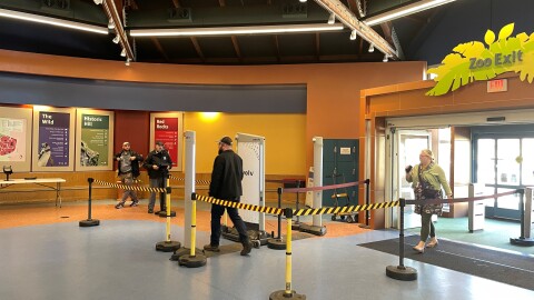 A man walks through the St. Louis Zoo's new Evolv security system while a security guard looks on.