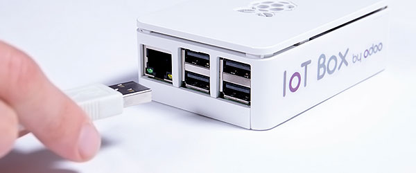 Una mano che collega uno spinotto USB alla IoT box di Odoo