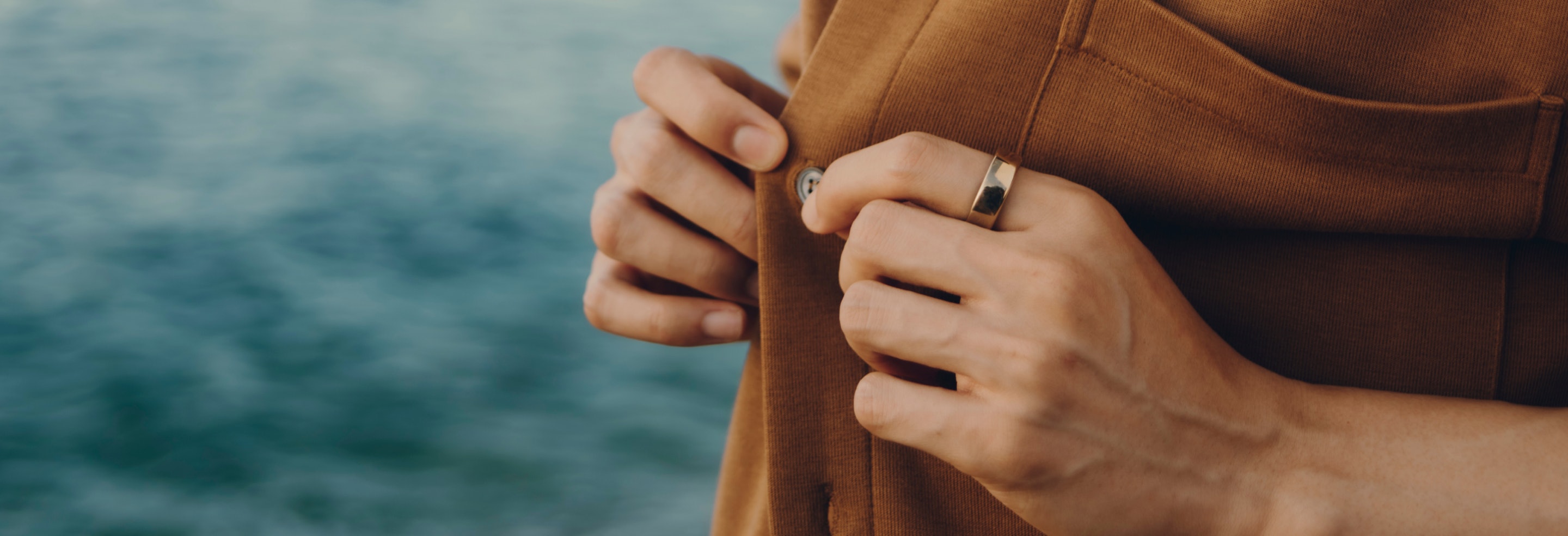 Person buttoning up shirt while wearing an Oura Ring