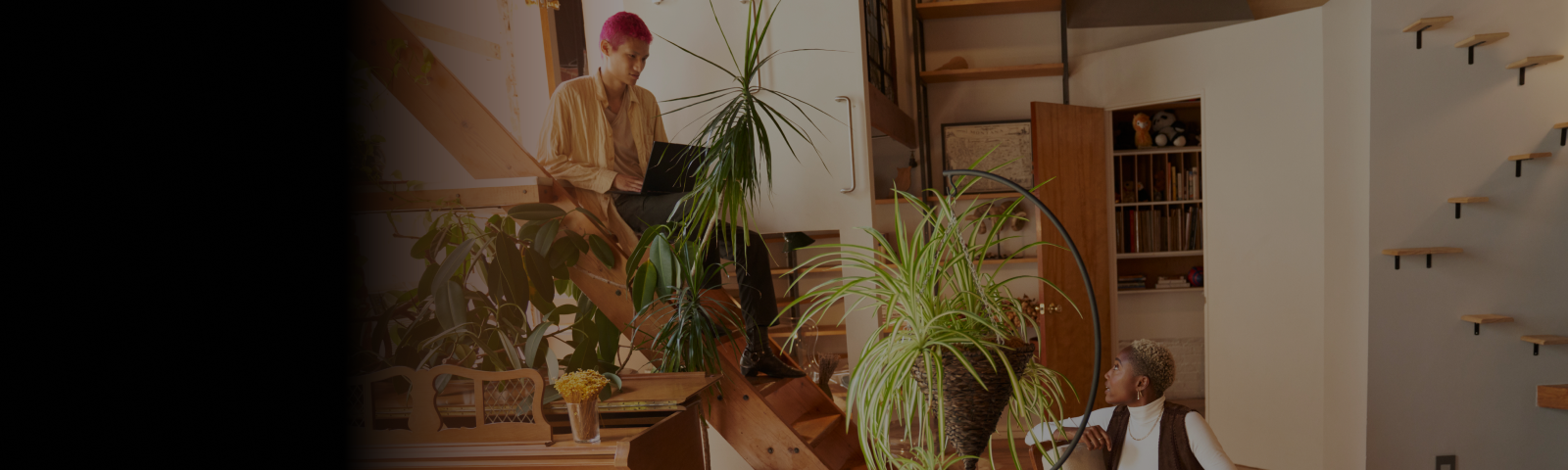 A person sitting on stairs with a laptop talking to another person