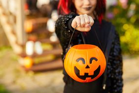 Closeup of unrecognizable little girl wearing Halloween costume and holding pumpkin basket in trick or treat season