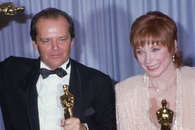 American actors Jack Nicholson and Shirley MacLaine pose together in front of a blue curtain, holding their Oscars