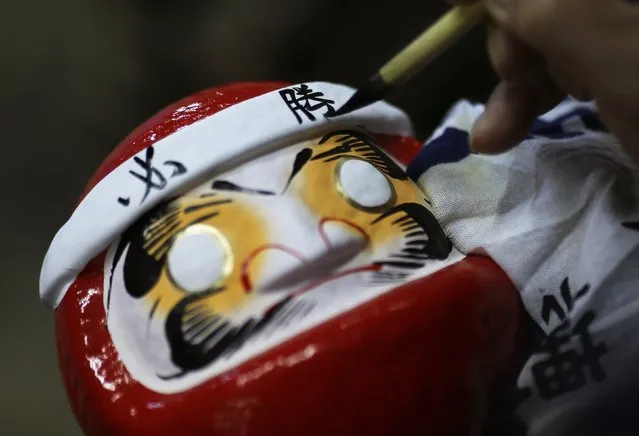 Japanese craftsman Sumikazu Nakata writes the Chinese character of “victory”, which is a part of the phrase “Certain victory”, as he adds the final touches on a Daruma doll, which is believed to bring good luck, at his studio “Daimonya” in Takasaki, northwest of Tokyo November 23, 2014. (Photo by Yuya Shino/Reuters)