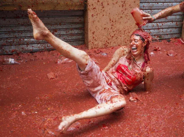 A reveller covered in tomato pulp takes part in the annual “Tomatina” festival in the eastern town of Bunol, on August 30, 2017. The iconic fiesta – which celebrates its 72nd anniversary and is billed at “the world's biggest food fight” – has become a major draw for foreigners, in particular from Britain, Japan and the United States. (Photo by Jaime Reina/AFP Photo)