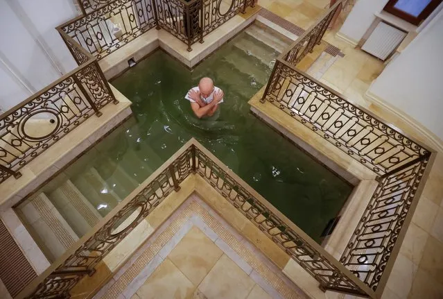 A man takes a dip inside a chapel during celebrations of the Orthodox Christian feast of Epiphany in Saint Petersburg, Russia on January 19, 2020. (Photo by Anton Vaganov/Reuters)