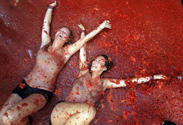 Two woman lie in a puddle of squashed tomatoes during the annual “Tomatina” tomato fight fiesta, in the village of Bunol, 50 kilometers outside Valencia, Spain, Wednesday, August 26, 2015. The streets of an eastern Spanish town are awash with red pulp as thousands of people pelt each other with tomatoes in the annual "Tomatina" battle that has become a major tourist attraction. (Photo by Alberto Saiz/AP Photo)