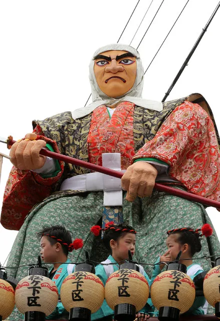 Children dressed in festival costume sit on the huge paper doll of historical Japanese figure named Hashi-Benkeii on the carts during the Mikuini annual festival on May 20, 2014 in Sakai, Japan. The annual festival takes place from May 19-21 and is attended by thousands of visitors. During the festival people dressed in traditional Japanese costumes pull carts carrying 6 meter high dolls of Japanese historical figures through the narrow streets. The origins of the festival are unclear but its history can be traced back more than 250 years. (Photo by Buddhika Weerasinghe/Getty Images)