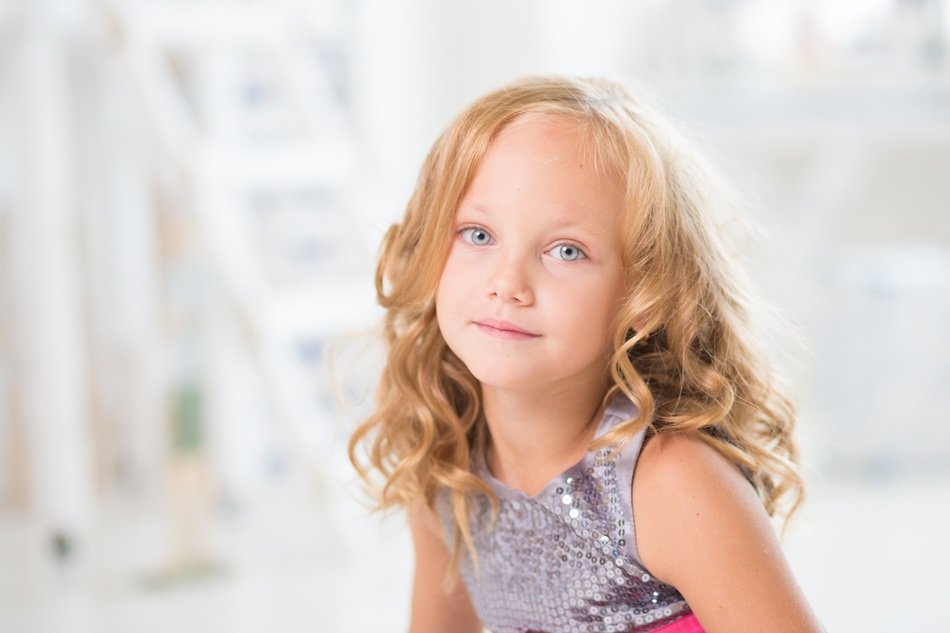 Portrait of the cute, blonde girl child with blue lights, on the square ...