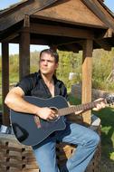 young Man posing with black guitar outdoor