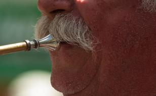 musical instrument in the mouth of a musician with a mustache