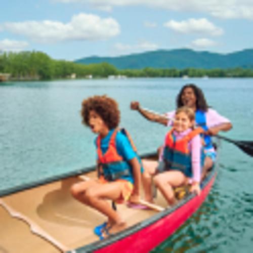 Due bambini e un adulto ridono mentre vanno in canoa sul lago. 