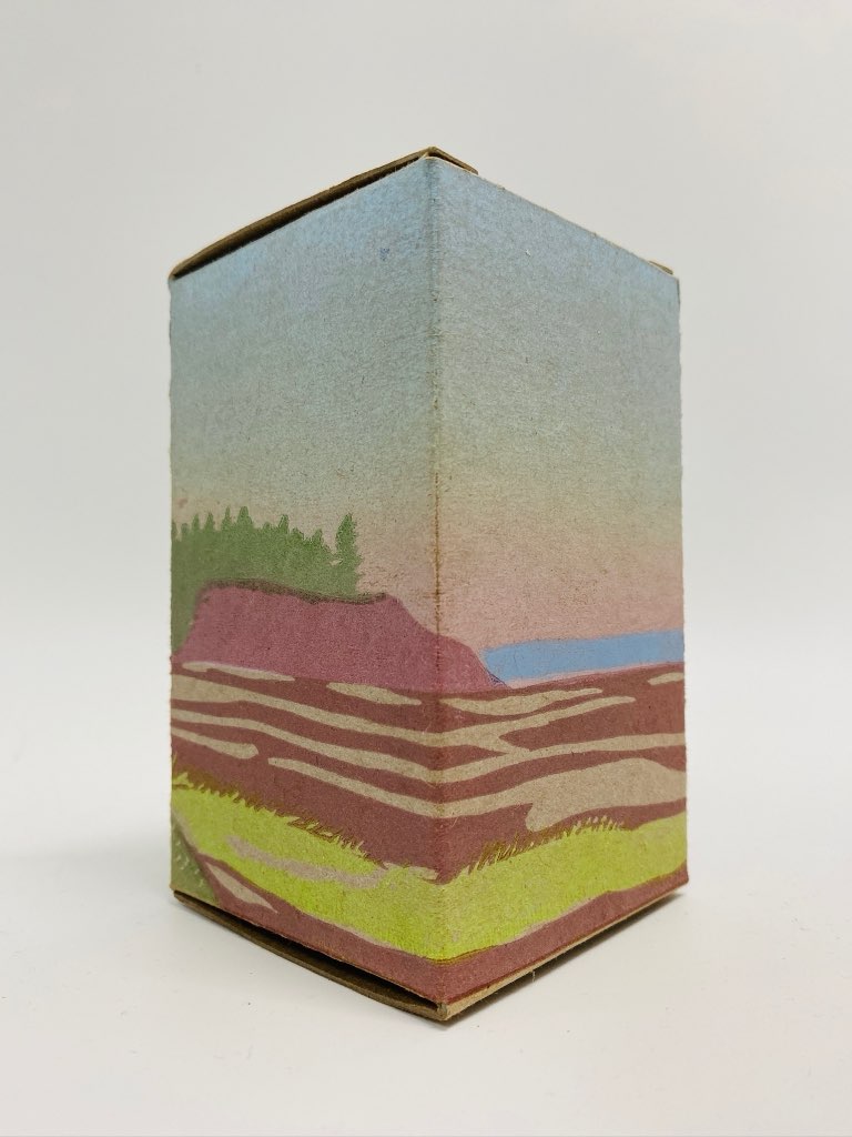 A single box in the This Box is for Good July edition, showing two sides of three of a rendering of the shore, water, and cliffs of Kinlock Beach.