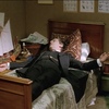 sherlock holmes, played by jeremy brett in the show by granada, dramatically laying down on his bed. His arm is hanging off the side and his fave appears tired or exasperated.