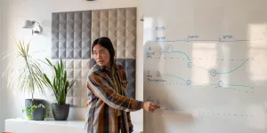 Jerlyn in front of a whiteboard mapping out the user journey