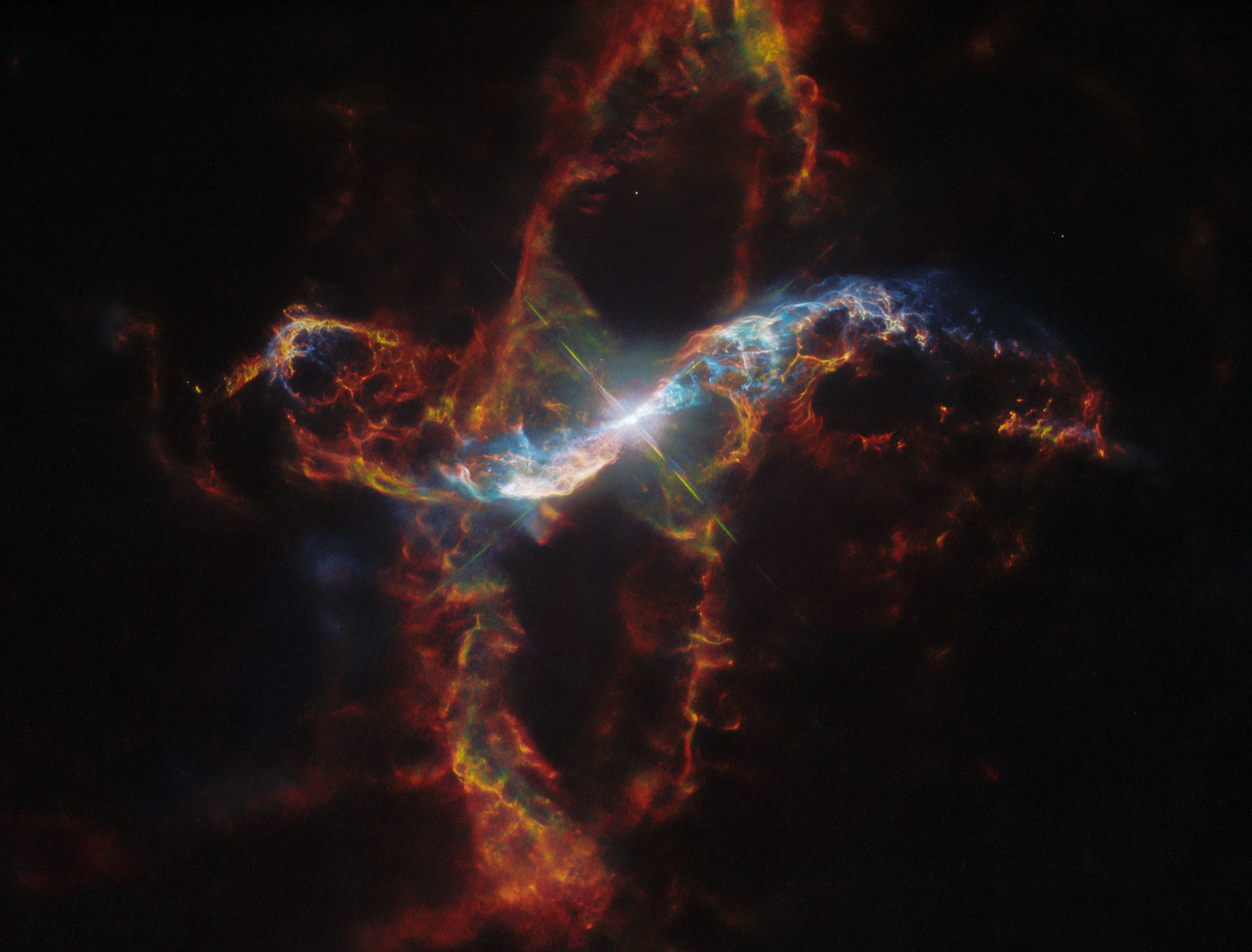 A bright binary star surrounded by a colorful loops of nebula on the black background of space. One loop is vertical the other is horizontal across the center of the image.