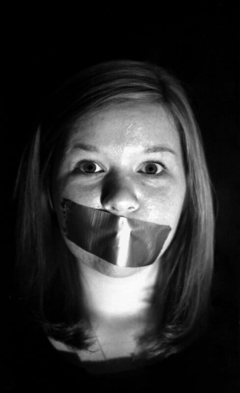 Portrait photo of a woman with tape over her mouth. Photo by Katie Tegtmeyer, CC-BY.