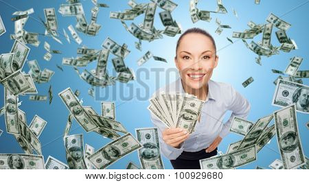 business, money, finance, people and banking concept - smiling businesswoman with heap of dollar cash money over blue background