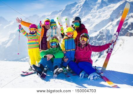 Family ski vacation. Group of skiers in Swiss Alps mountains. Adults and young children teenager and baby skiing in winter. Parents teach kids alpine downhill skiing. Ski gear and wear safe helmets.