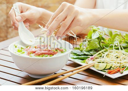 Young Woman Sprinkles Sprouts To The Pho Bo In Cafe Of Vietnam