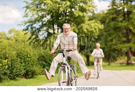 active old age, people and lifestyle concept - happy senior couple riding bicycles at summer park