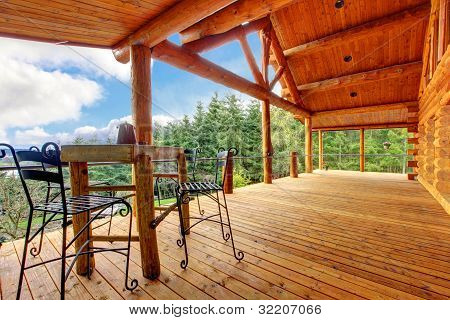 Porch Of The Log Cabin With Small Table And Forest View.