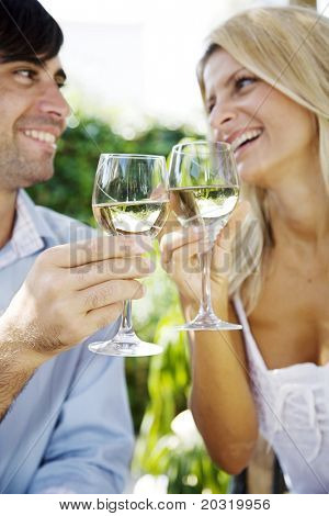 young couple enjoying a glass of white wine in the garden on a summer day