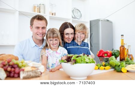 Smiling Parents And Their Children Preparing Dinner Together