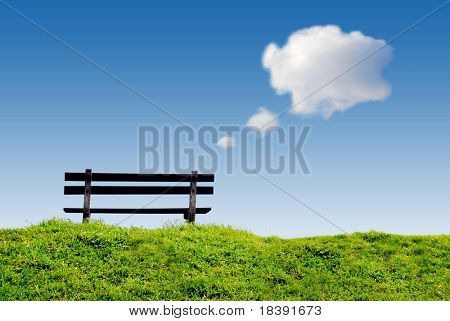 bench on green grass with conceptual text-balloon thinking and day dreaming clouds in clear blue sky