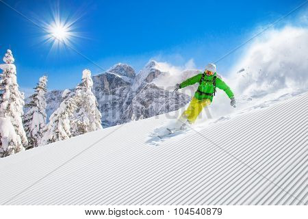 Skier skiing downhill during sunny day in high mountains