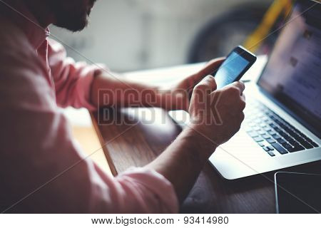 Rear view of business man hands busy using cell phone at office desk