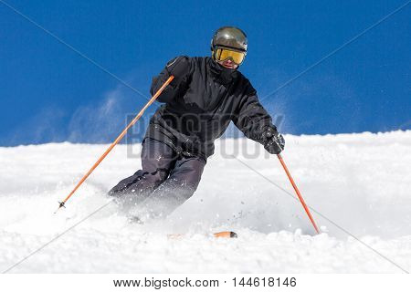 Male skier skiing in fresh snow on ski on a sunny winter day at the ski resort Soelden in Austria.