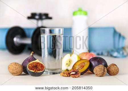 Healthy lifestyle concept. Diet and fitness. Healthy lifestyle style. Water and fruit as a healthy food on a background of blurry fitness equipment. Proper nutrition and active healthy lifestyle.