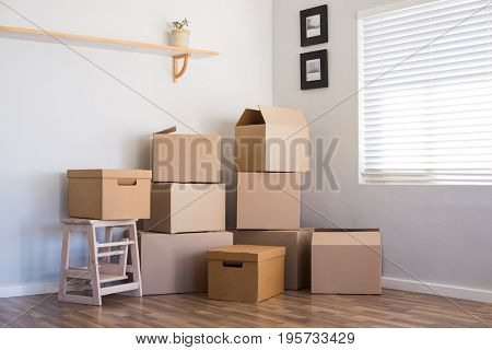 Stack of cardboard boxes in an empty room. Pile of carton boxes on the floor in an empty apartment. Stack of moving boxes in new house.