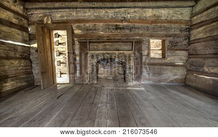 Pioneer Log Cabin Interior. Wooden interior of historic pioneer cabin living room with hardwood floor and fireplace.