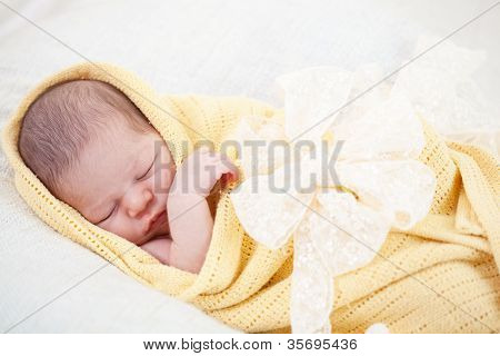 sleeping newborn baby wrapped in a yellow blanket