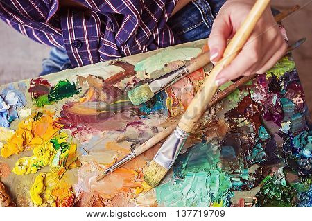 Brush And Oil Paints On A Palette, Paint A Picture Of The Artist's Hands, Texture Mix Paint In Diffe