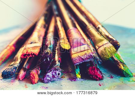 Artist paintbrushes with paint closeup on artistic canvas. Retro toned. Selective focus.