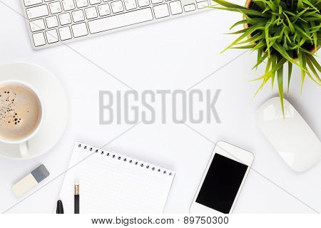 Office desk table with computer, supplies, flower and coffee cup. Top view with copy space