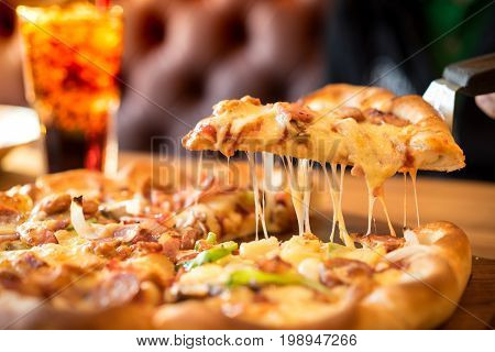 Slice of pizza cheese crust seafood topping sauce. with bell pepper vegetables delicious tasty fast food italian traditional and soft drink carbonated fresh on wooden board table classic in side view