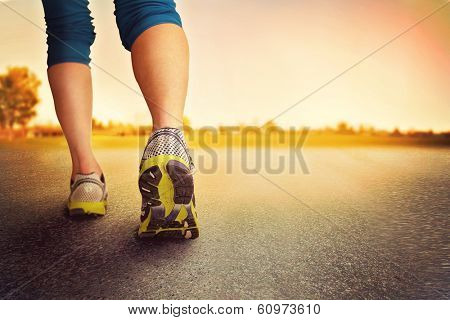 an athletic pair of legs on pavement during sunrise or sunset - healthy lifestyle concept