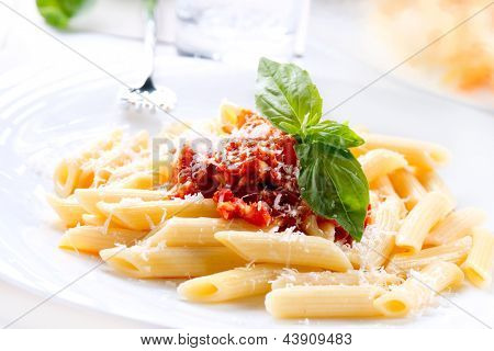 Pasta. Penne Pasta met saus Bolognese, Parmezaanse kaas en basilicum op een vork. Italiaanse keuken. Medit