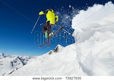 Alpine skier skiing downhill, blue sky on background