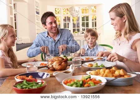 Happy family having roast chicken dinner at table