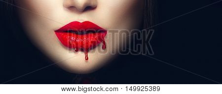 Beauty Sexy Vampire red lips with dripping blood close up. Isolated on black background. 