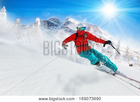 Skier skiing downhill during sunny day in high mountains