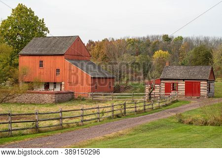 Historic Colonial American Farm Scene, Dirt Road, Log Cabin And Red Barn On The Historic Daniel Boon